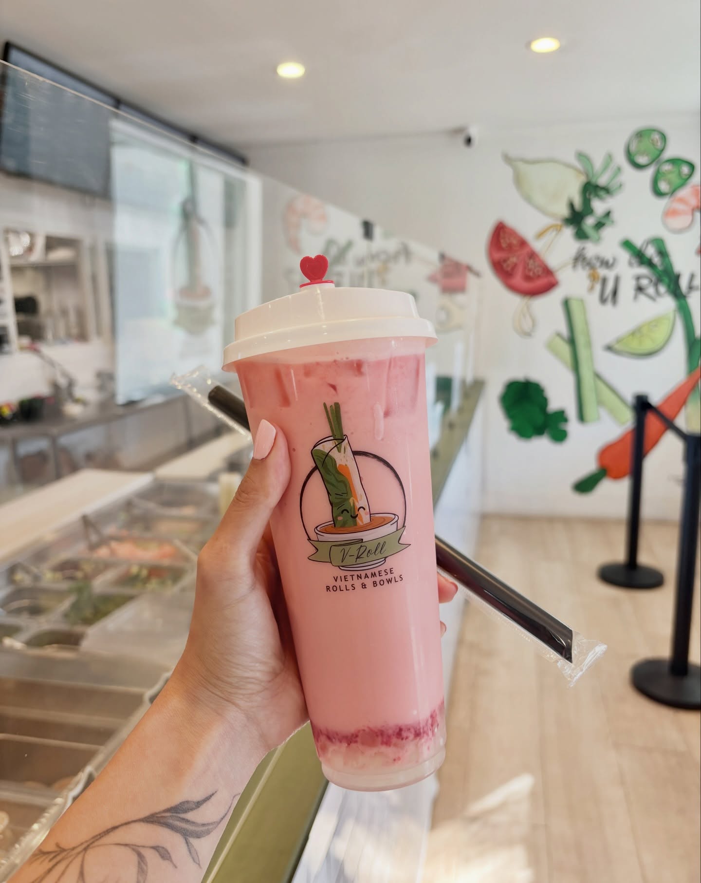 A pink V-Roll milk tea held up inside the dining room