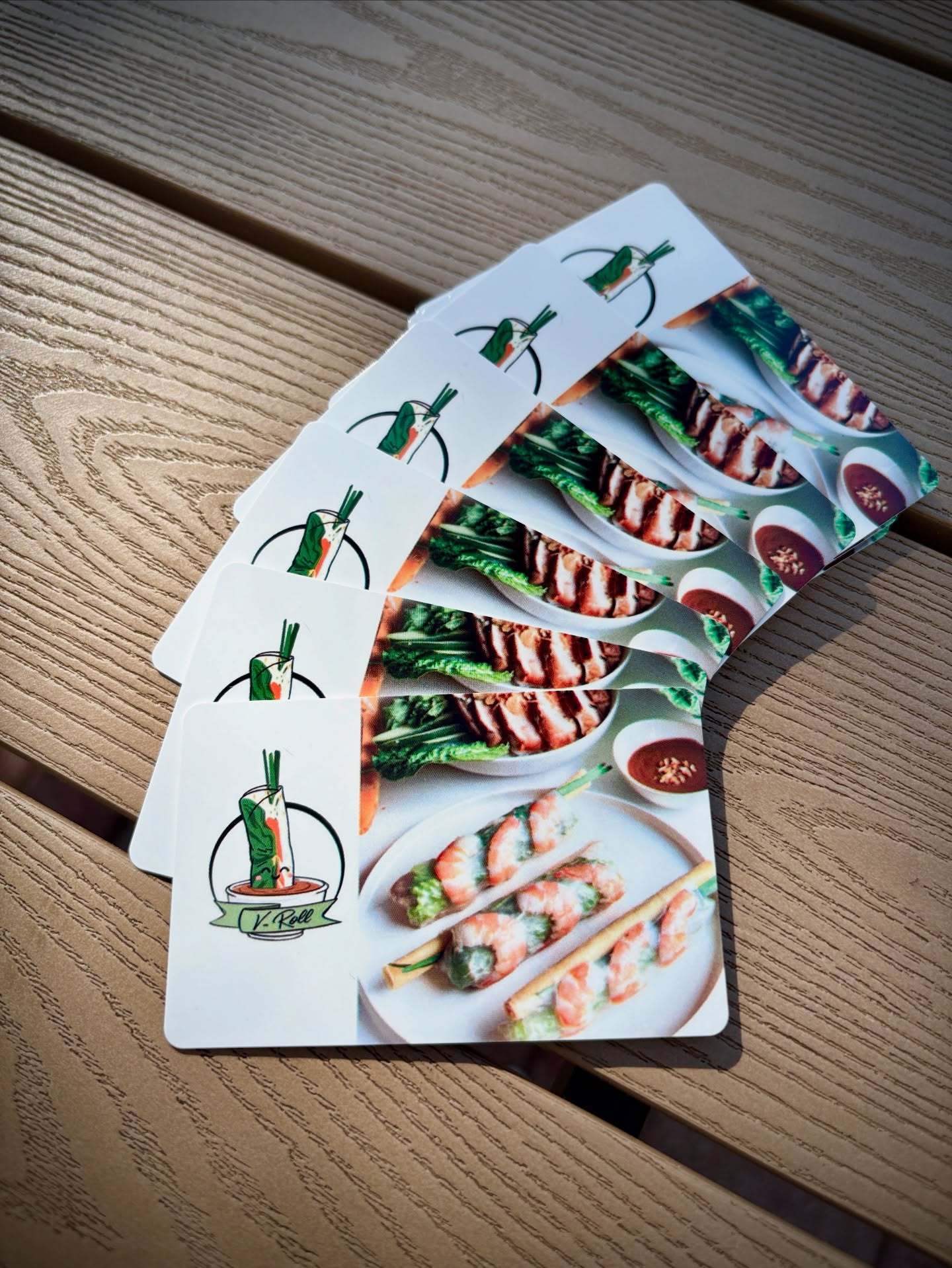 A fan of V-Roll gift cards on a wood table