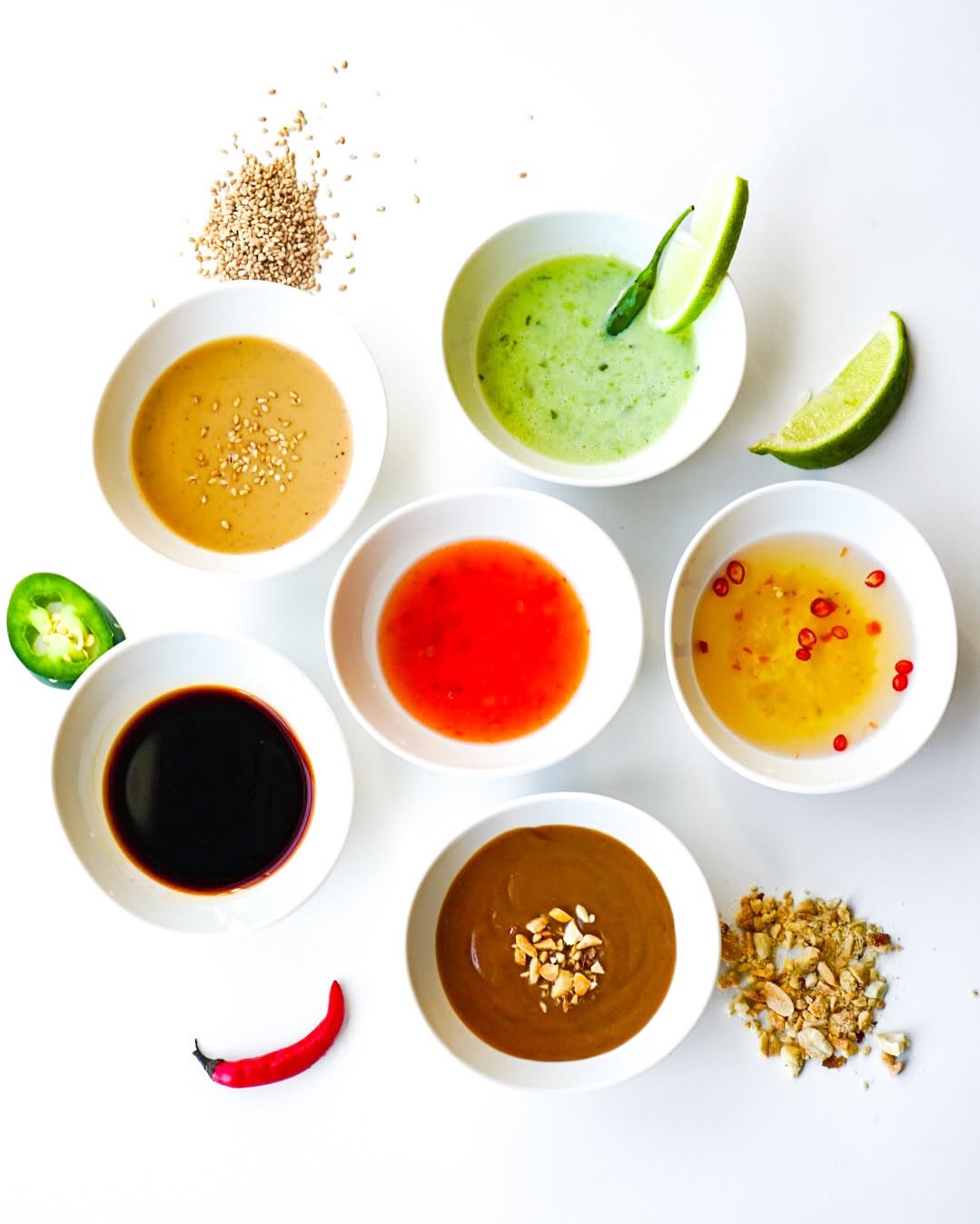 Six V-Roll house sauces in white ramekins with lime and chili